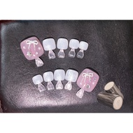 Pink and white glitter toe nails with bow charms for a sweet and cute style