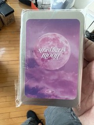 IU 李知恩 的官方周邊「Strawberry Moon」小卡套裝，配有金屬鐵盒。鐵盒封面上印有粉紅色的「Strawberry Moon」月亮圖案與歌詞。商品通常包含多張小卡，部分版本包含拍立得和小貼