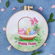 DIY 手工刺繡復活節彩蛋在彩繪背景織物上的籃子裡。 刺繡套件包