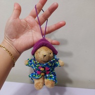 -` ́- Paddington Bear Iconic Blue Duffel Coat with Pink Toggles and a Purple Hat Bag Charm