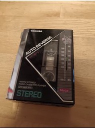 Toshiba KT-V670 卡式錄音機，具有 AM/FM 立體聲收音機和自動反向功能。支援金屬磁帶。頂部有音量控制、調諧和耳機插孔。錄音機背面有型號和規格。錄音機外觀有使用痕跡 MADE IN J