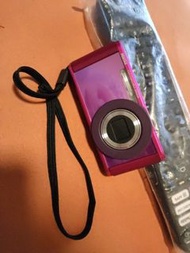 Pentax Optio LS465 數位相機，正常運作數碼相機粉紅色機身，配有相機帶。具有 5 倍變焦和 1600 萬像素。側面有開/關按鈕和插孔。底部有插槽，用於插入 SD 卡。包含遙控器。Pen