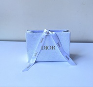 極新中型Dior（迪奧）專櫃白色紋理紙質禮品袋，正面印有品牌標誌性的金色 DIOR 字樣，並搭配印有品牌標誌的白色緞帶，通常用於包裝香水、口紅或護膚品等彩妝奢華禮品。7.75吋濶5.5吋高3吋高。