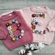 手工製作的美利奴羊毛毛衣，繡有女孩姓名縮寫。嬰兒禮物