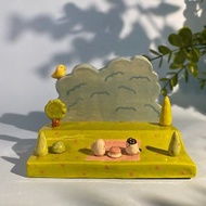 Cute handmade ceramic mobile phone holder with a pattern of little cats picnicking in the grass.